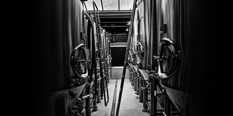 Cuve de fermentation en inox, lumière latérale sur métal brut | Unseen Brewing Co.